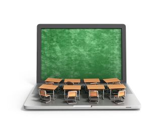 Student desks atop laptop computer with green screen like blackboard.