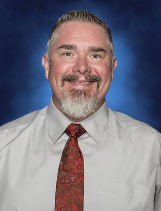 A headshot of Shad McGaha he is wearing a dress shirt and tie.